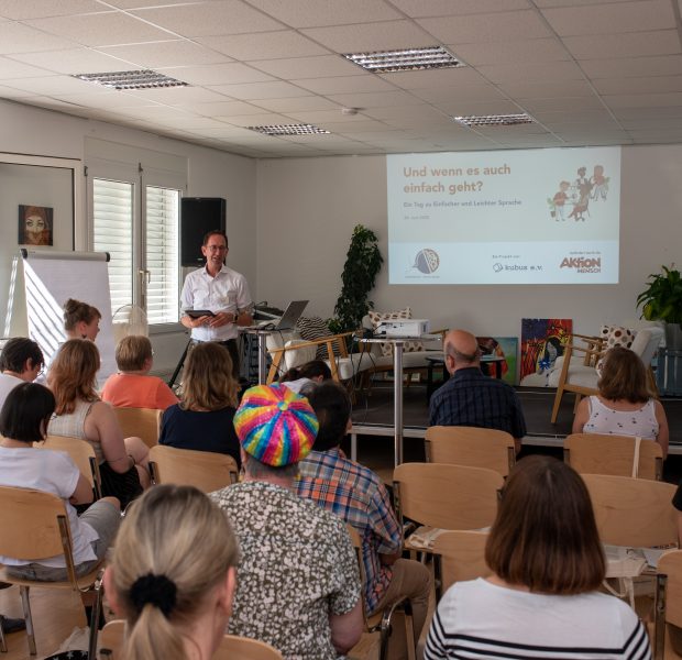 Auf dem Bild sieht man einen Vortrag mit Teilnehmenden aus dem Vorgängerprojekt.